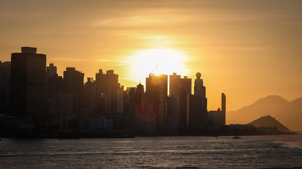 City skyline at sunset with warm glow and vibrant orange-yellow sky behind buildings