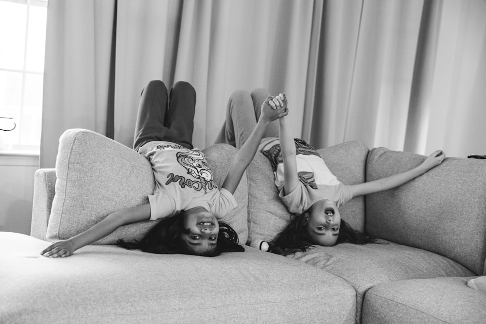 two girls laying on a couch with their legs up
