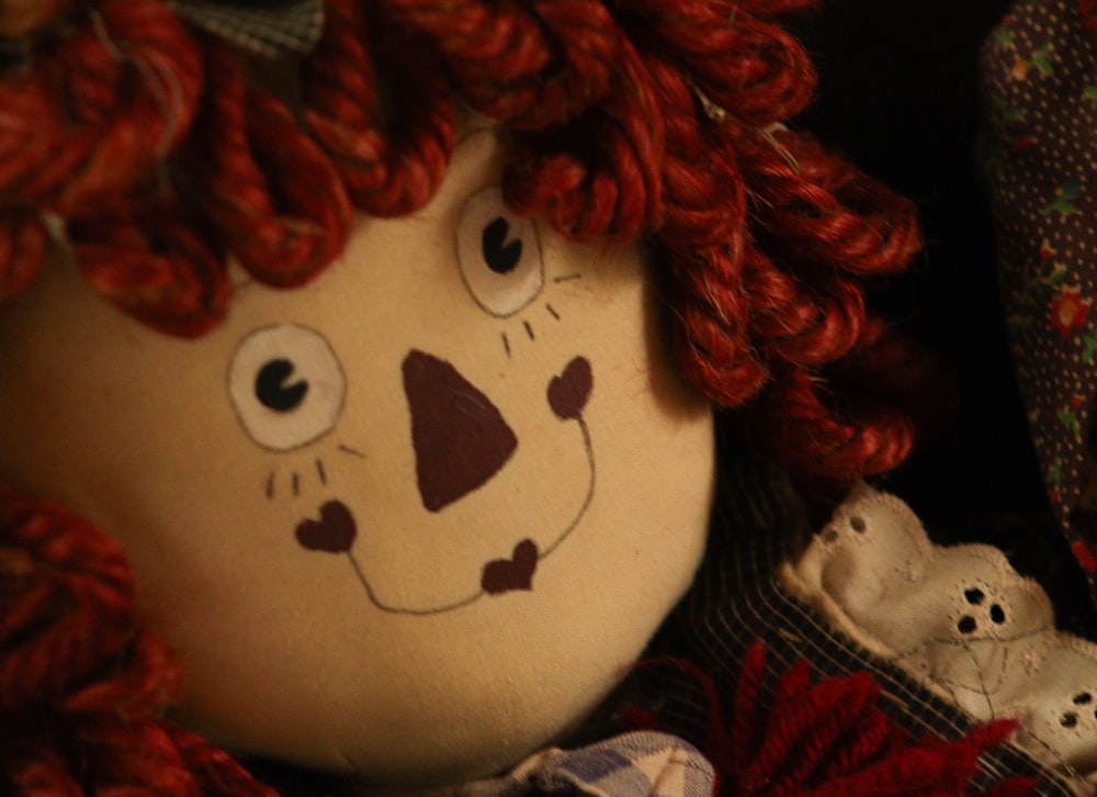 a close up of a stuffed animal with red hair