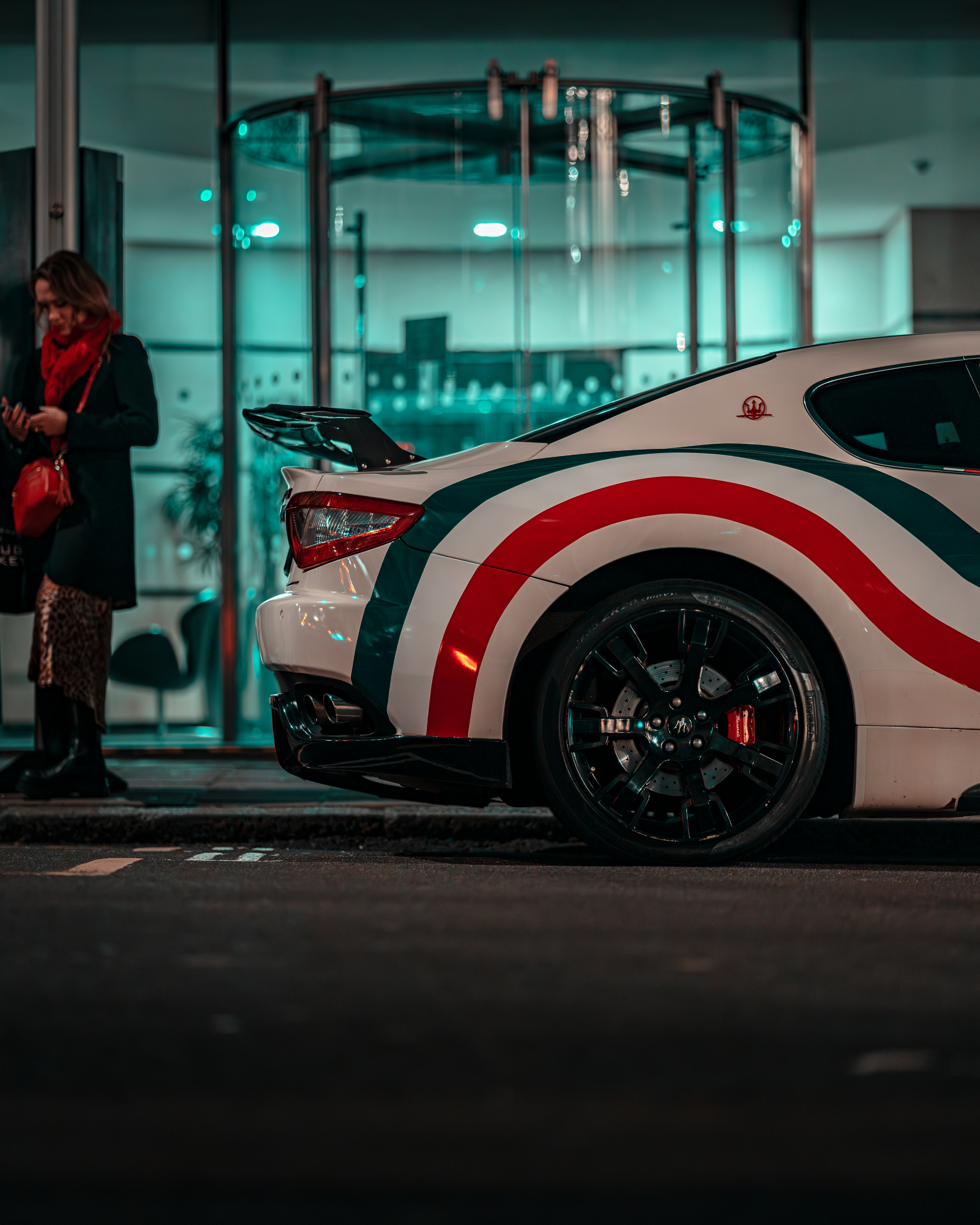 a woman standing next to a white and red car