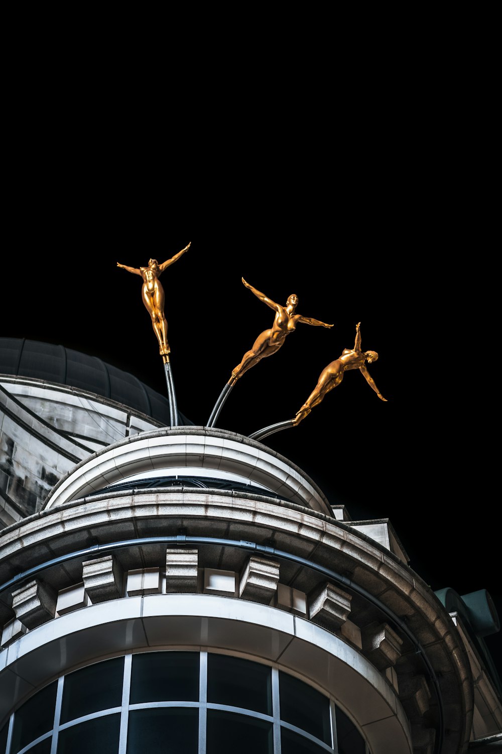 ein Gebäude mit drei Statuen auf der Spitze