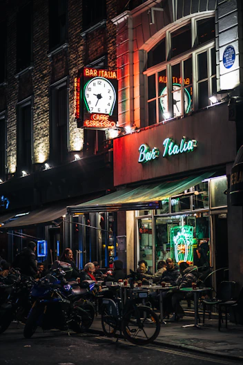 a group of people sitting outside of a restaurant at night