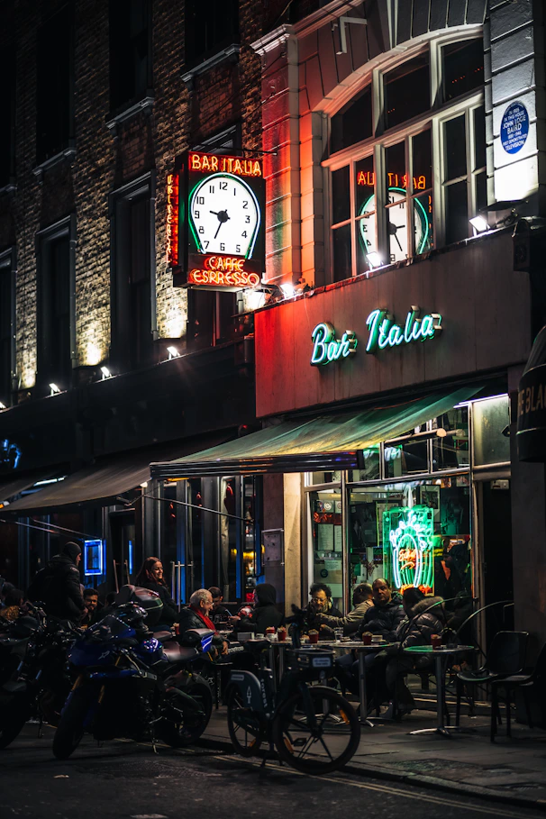 a group of people sitting outside of a restaurant at night