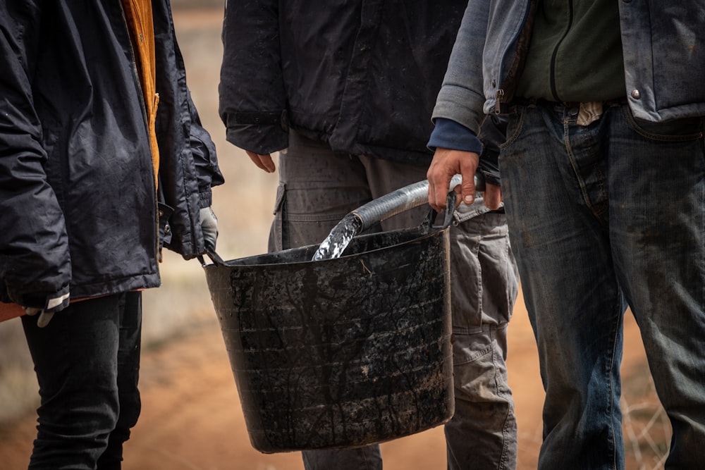 a group of people standing next to each other holding a bucket