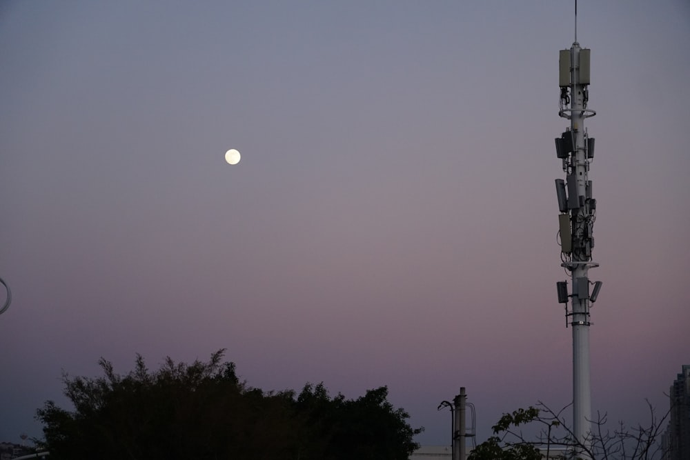 a cell phone tower with a full moon in the background