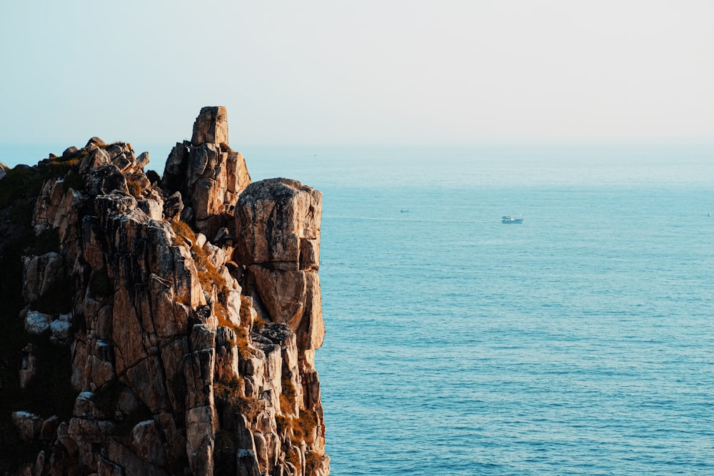 a boat is in the water near a rocky outcropping