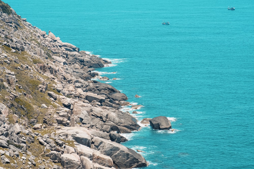 a boat is on the water near a rocky shore