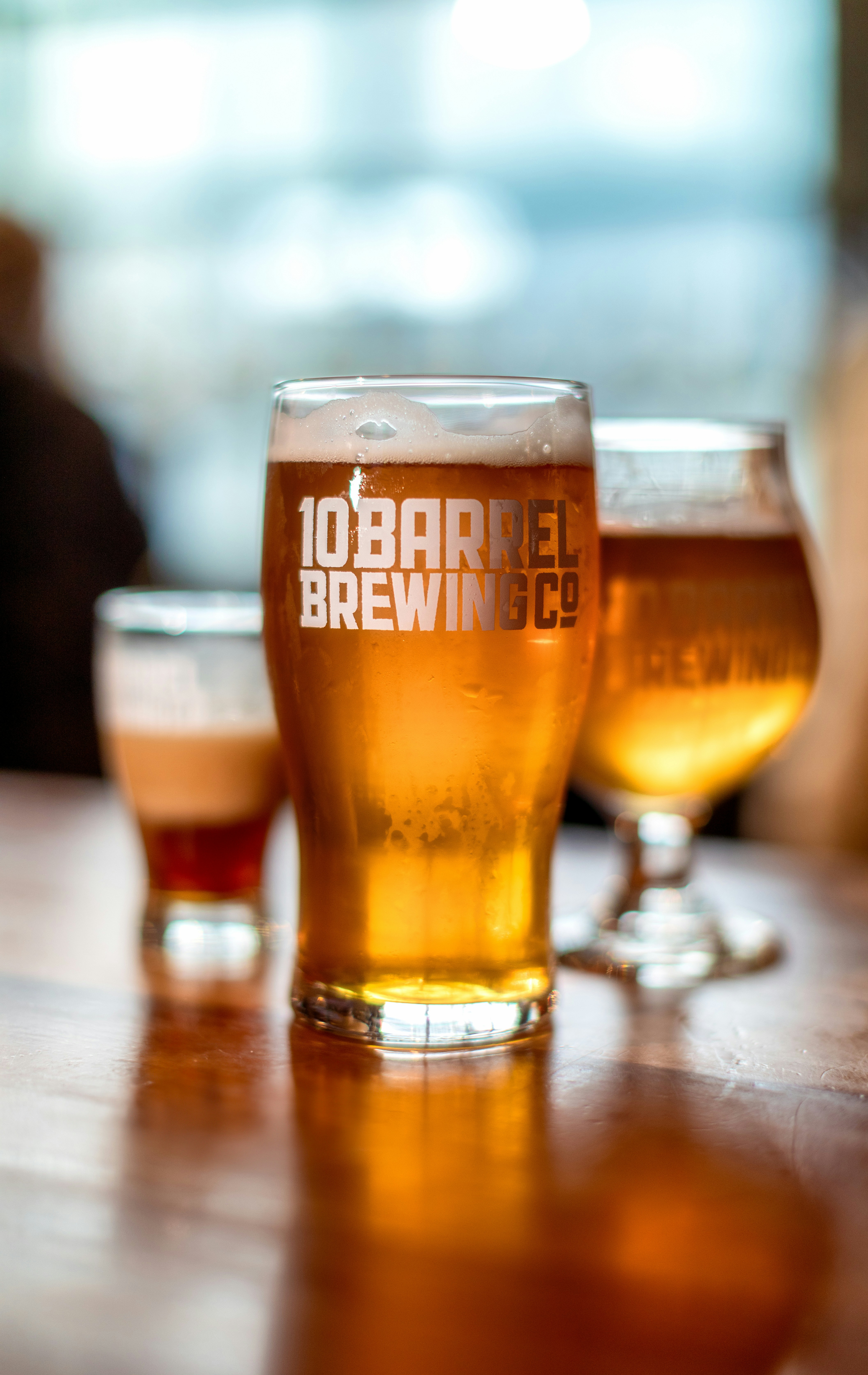 three glasses of beer sitting on top of a wooden table