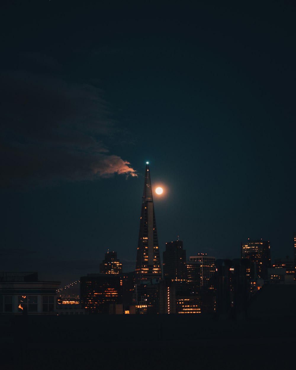 uma lua cheia nascendo sobre uma cidade à noite