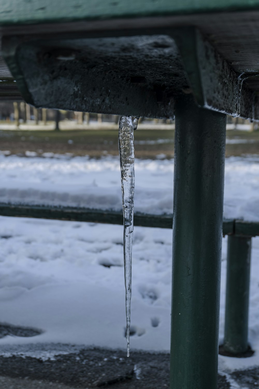 a long icicle hanging from the side of a bench