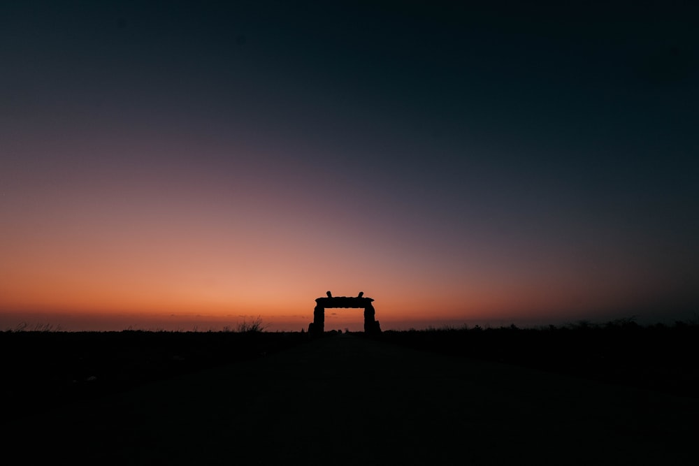 a silhouette of a gate in the middle of a field