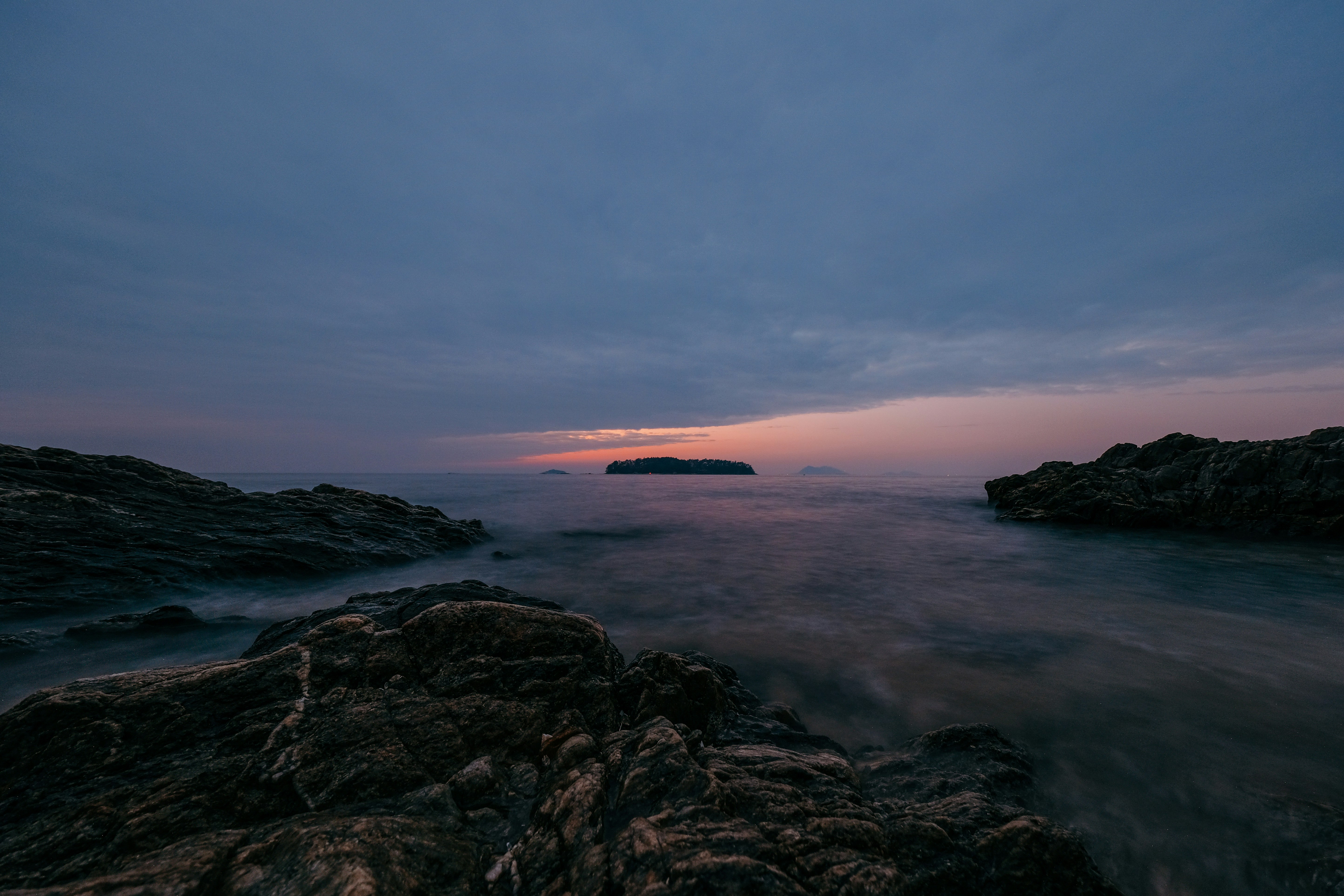 a body of water surrounded by rocks under a cloudy sky