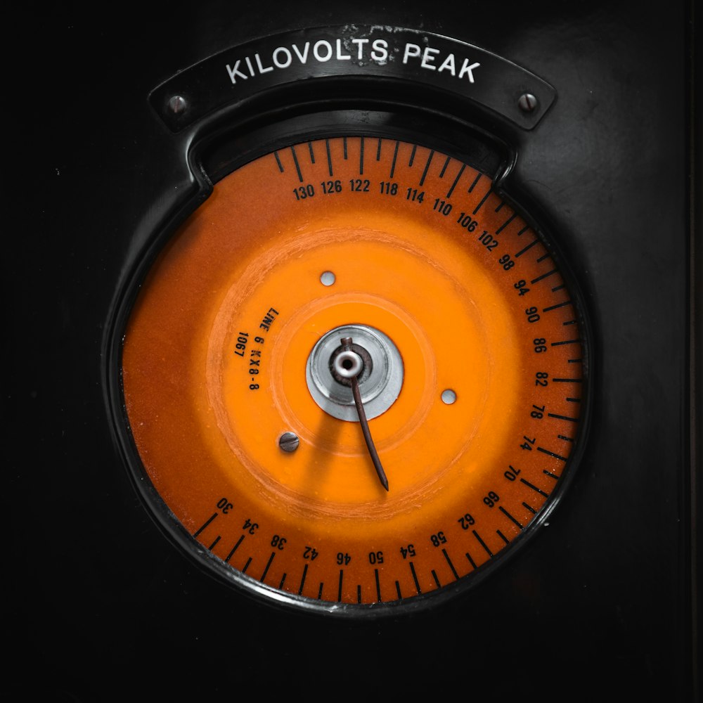 a close up of an orange and black clock
