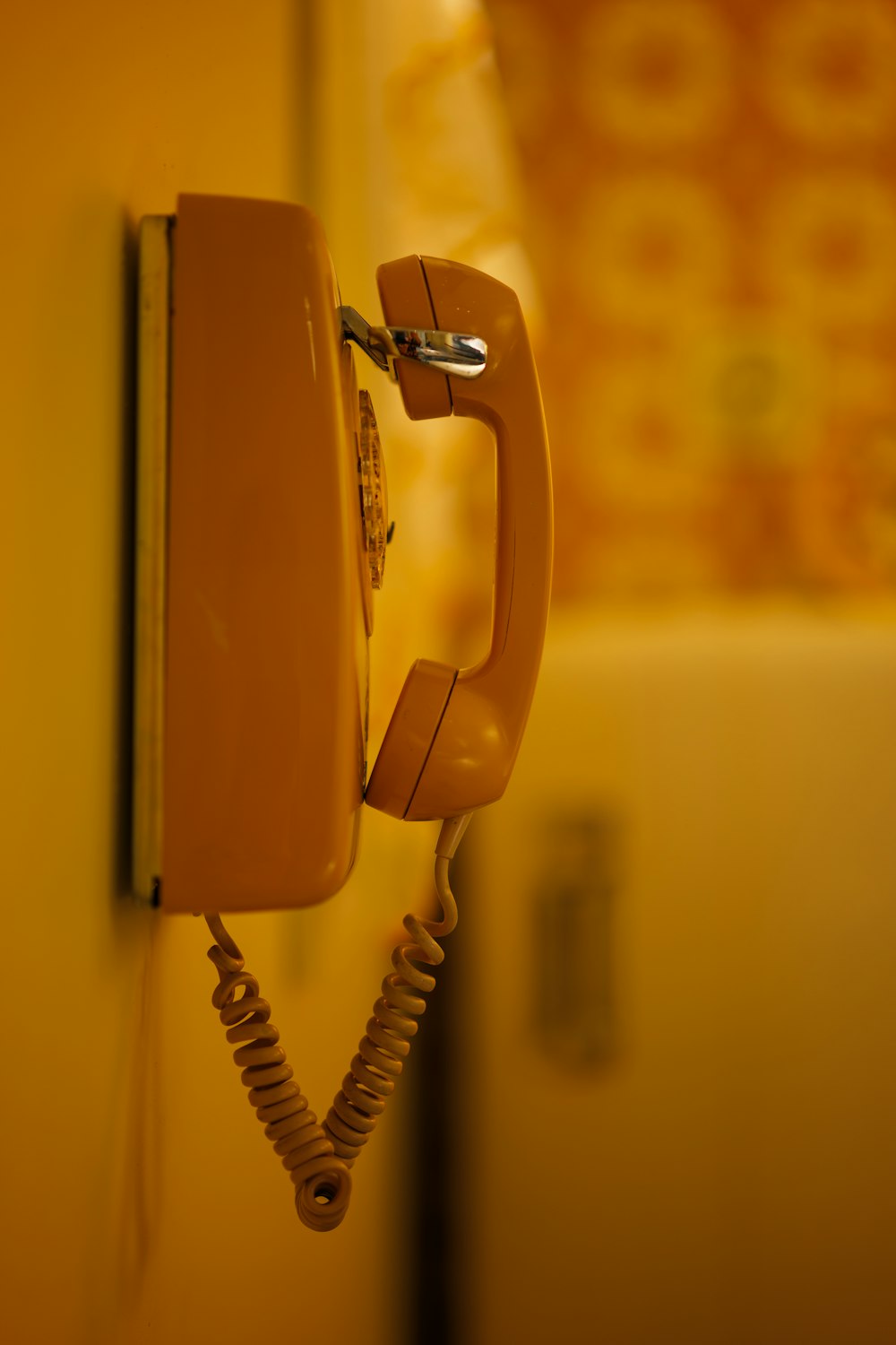 an orange phone is hanging on a wall