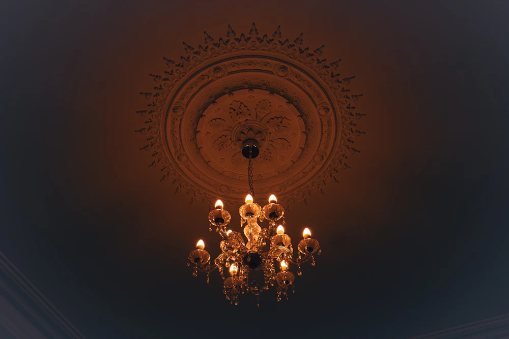 Candelabru de cristal aprins sub o rozetă de stuc