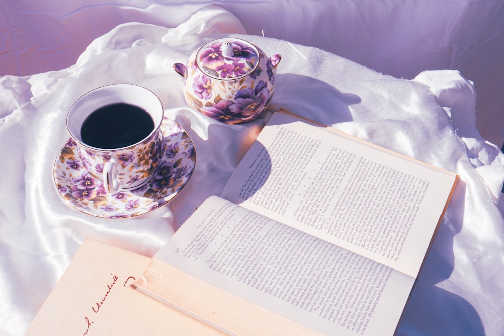 a cup of coffee and a book on a bed