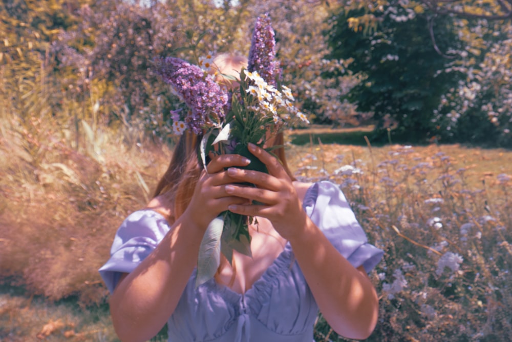 a woman holding a bunch of flowers in her hands