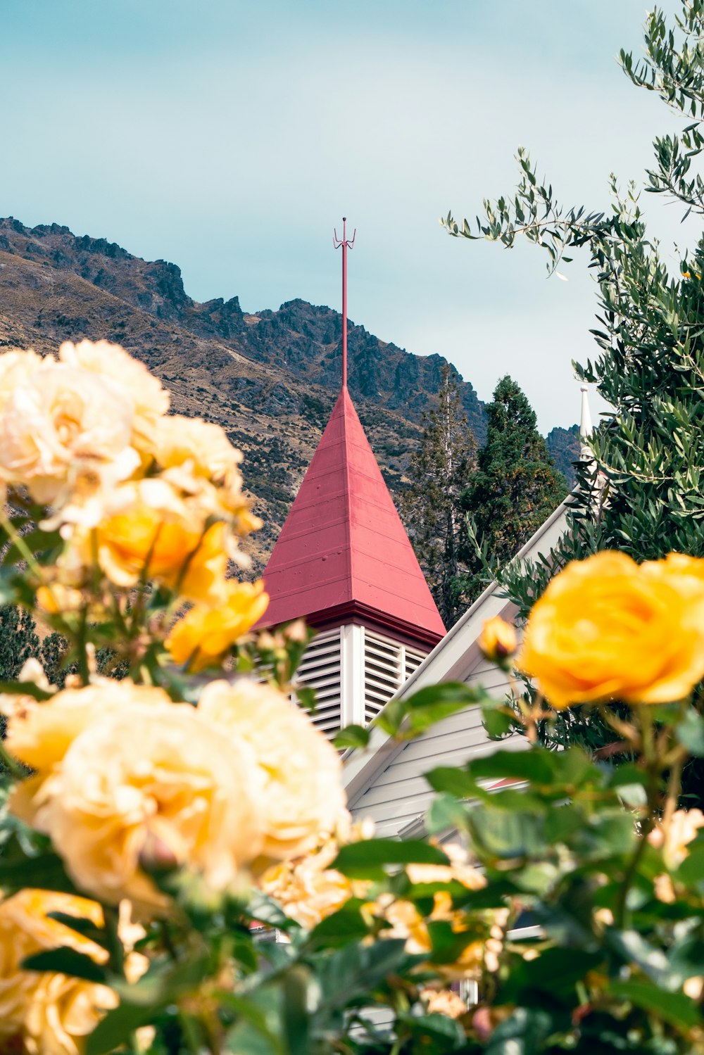 目の前に黄色い花が咲く教会の尖塔