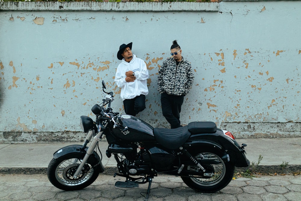 a couple of men standing next to a motorcycle