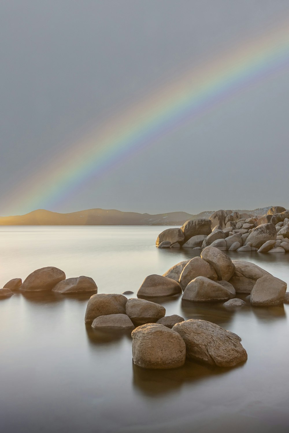 a rainbow shines in the sky over a body of water