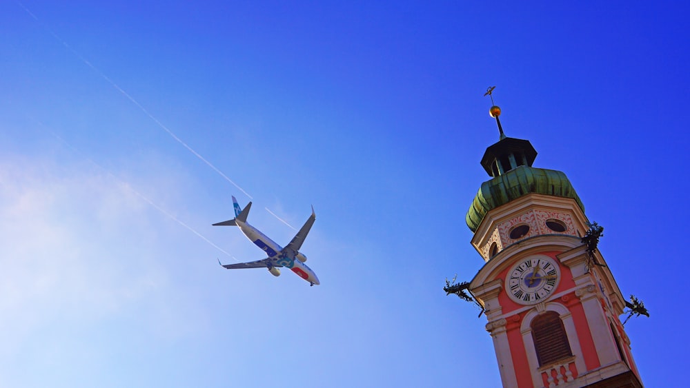 an airplane flying in the sky over a clock tower