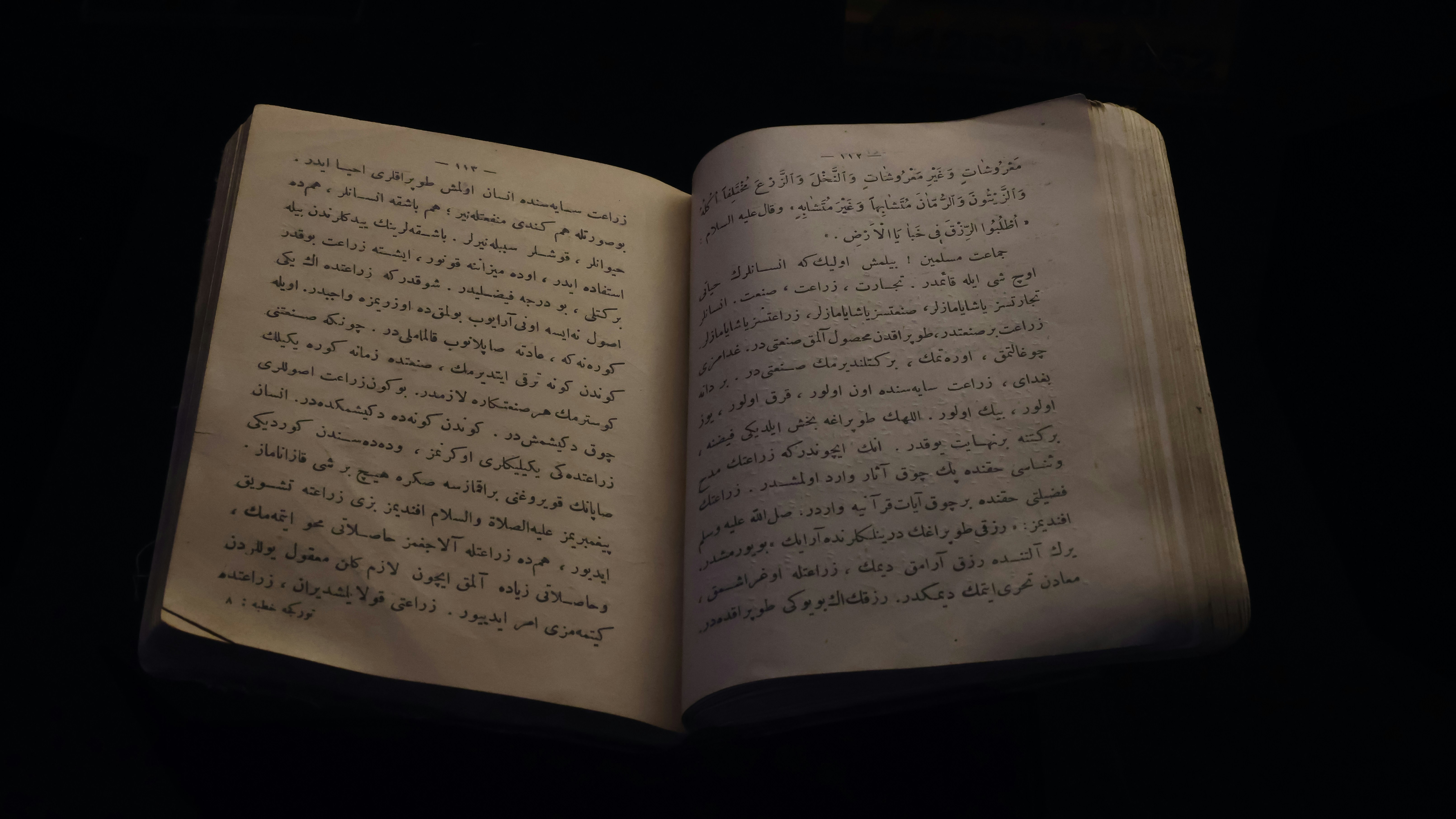 Photograph of an old, handwritten book on a black background