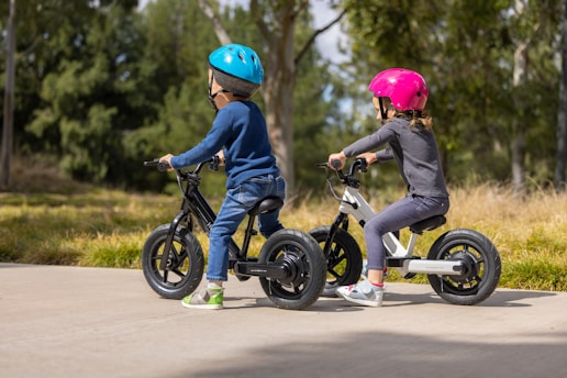 two young children riding bikes on a sidewalk