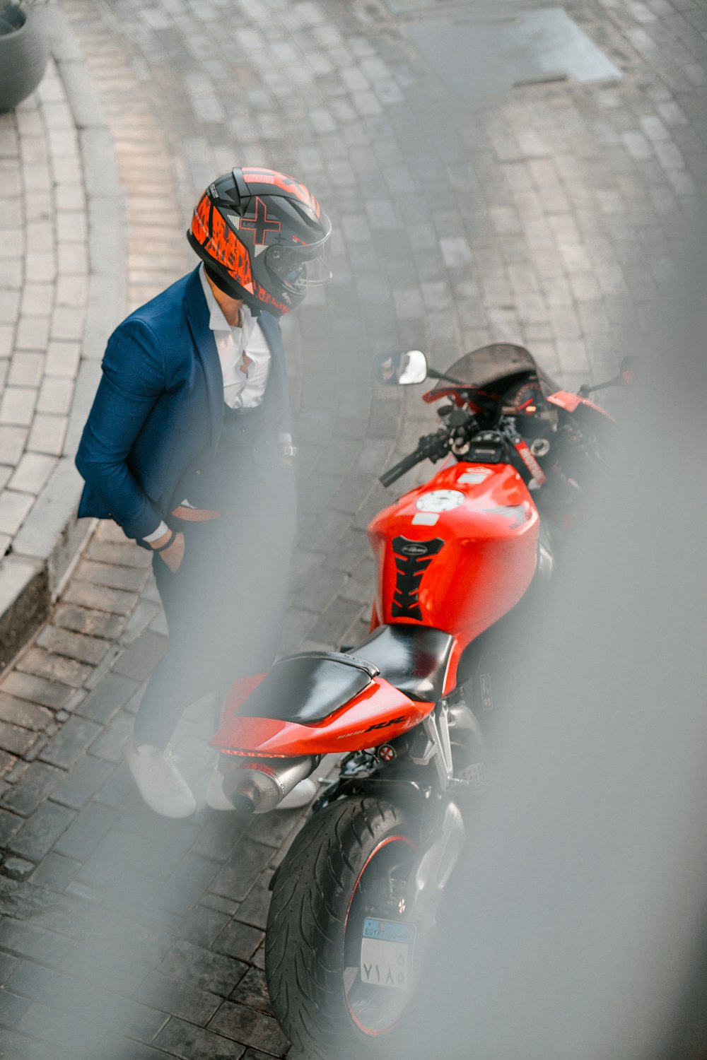 a man standing next to a red motorcycle