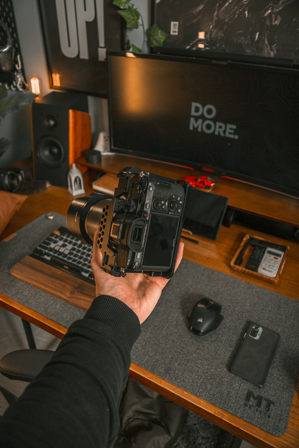 a person holding a camera in front of a computer