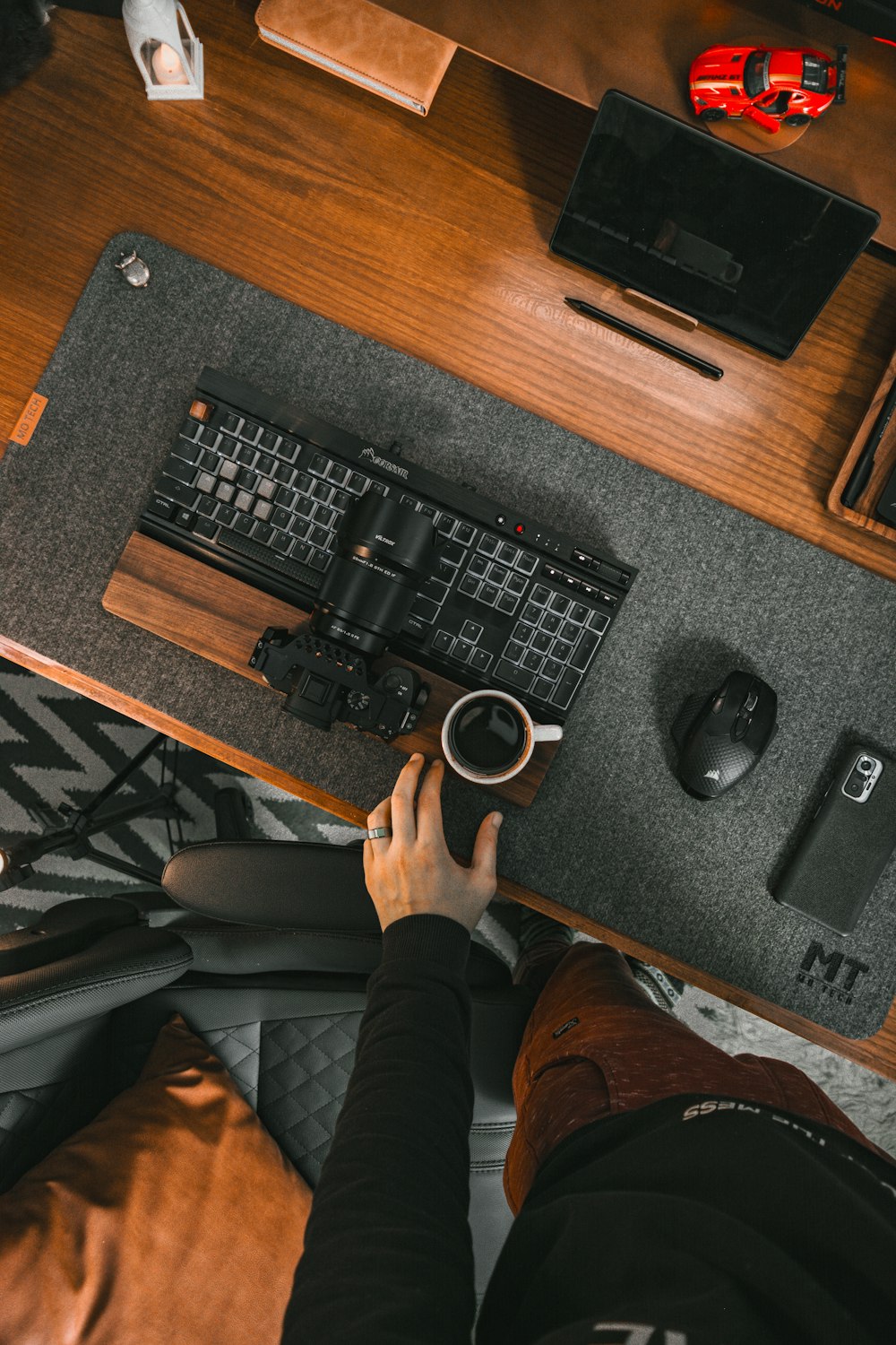 eine Person, die mit Tastatur und Maus an einem Schreibtisch sitzt