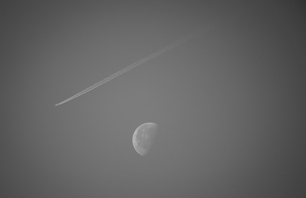 a plane flying past a half moon in the sky