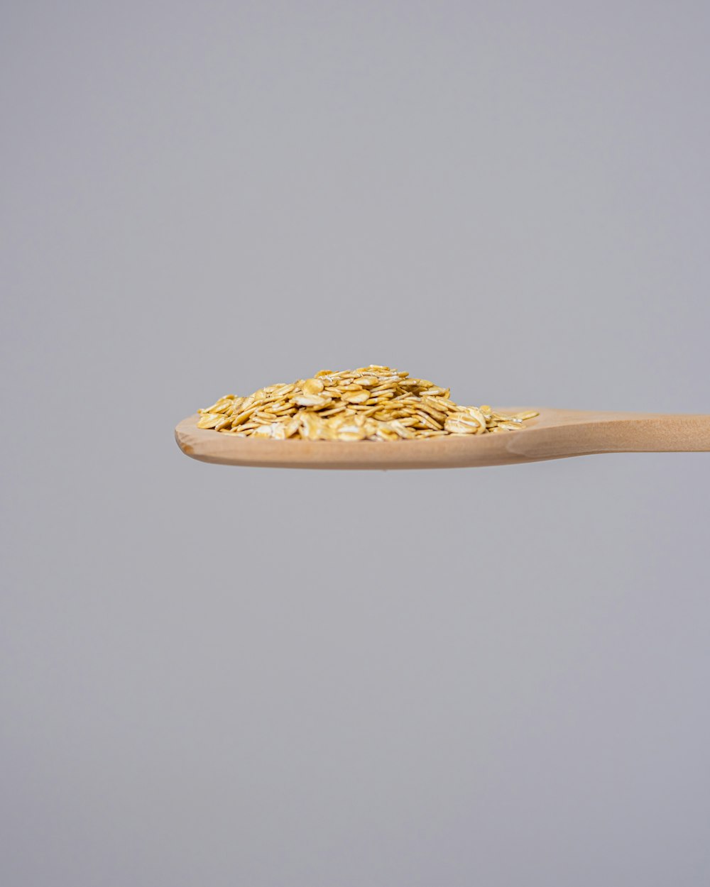 a wooden spoon full of oats on a gray background