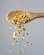 a wooden spoon filled with oats falling from it