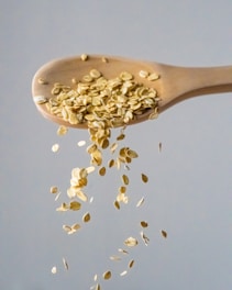 a wooden spoon filled with oats falling from it