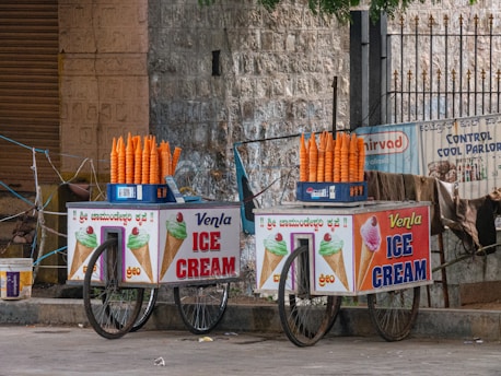 a couple of ice cream carts sitting on the side of a road