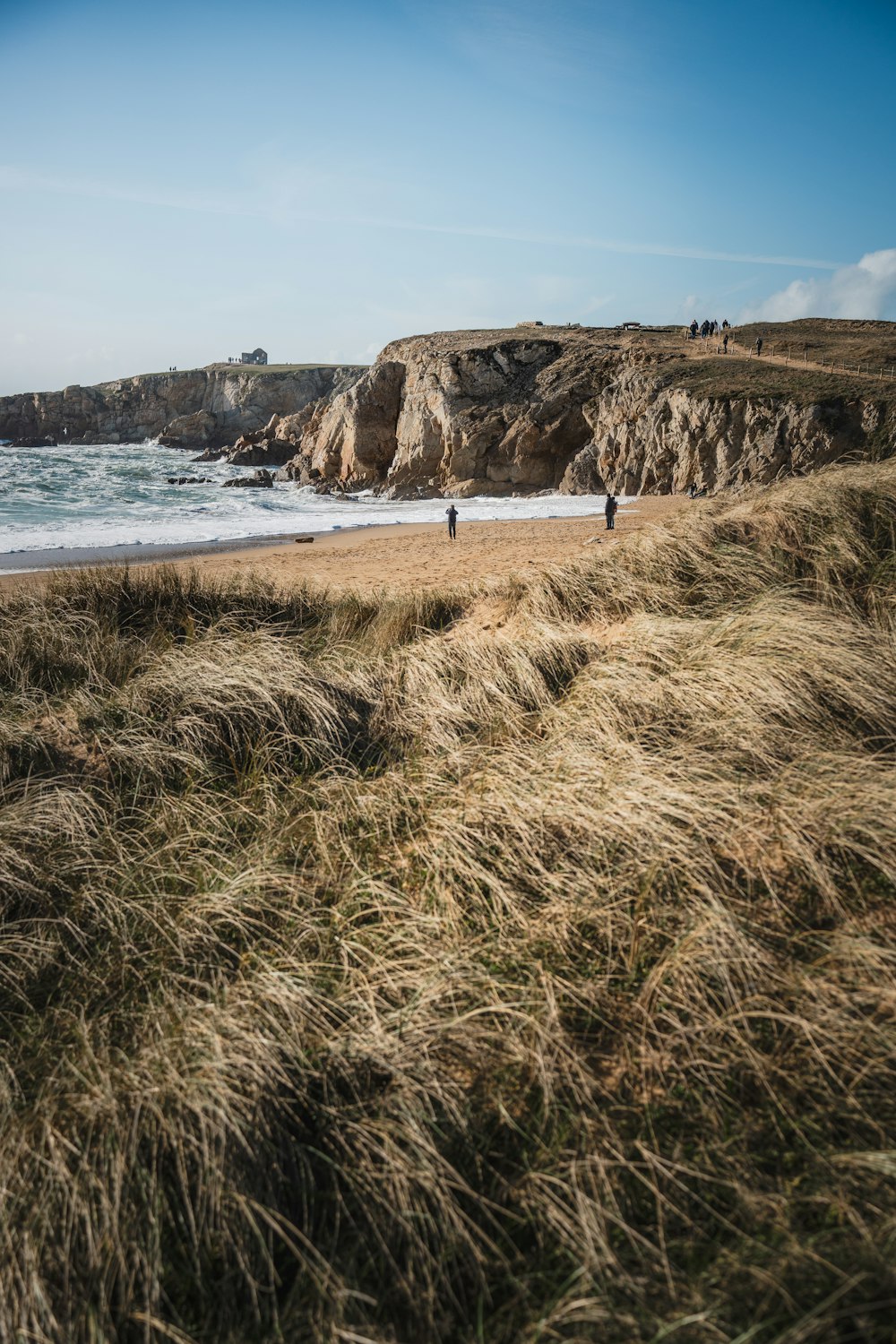 a couple of people standing on top of a sandy beach