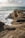 a person standing on top of a rocky cliff next to the ocean
