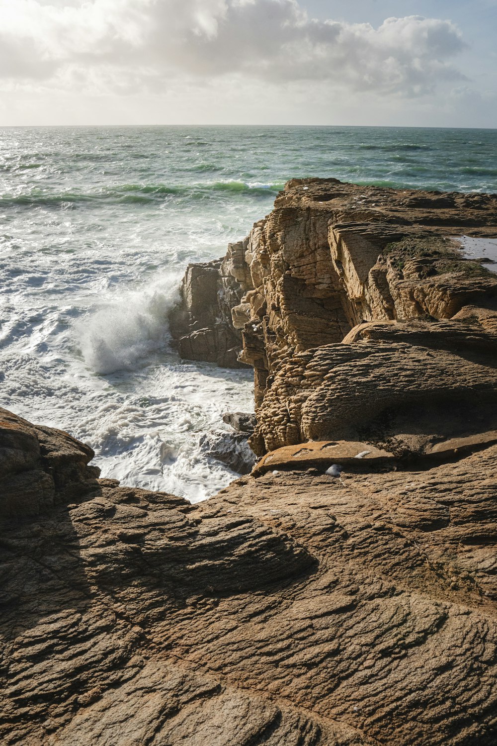 Una persona de pie en la cima de un acantilado rocoso junto al océano