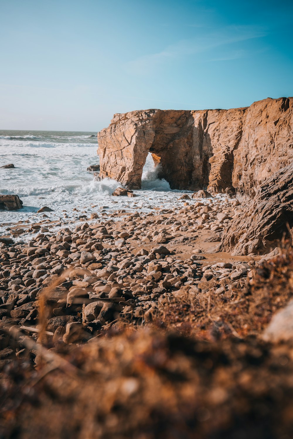 uma praia rochosa com um pequeno buraco no meio dela