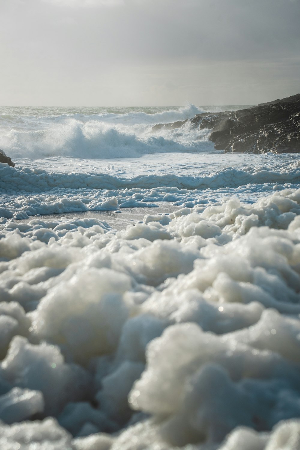 a beach covered in foam next to the ocean