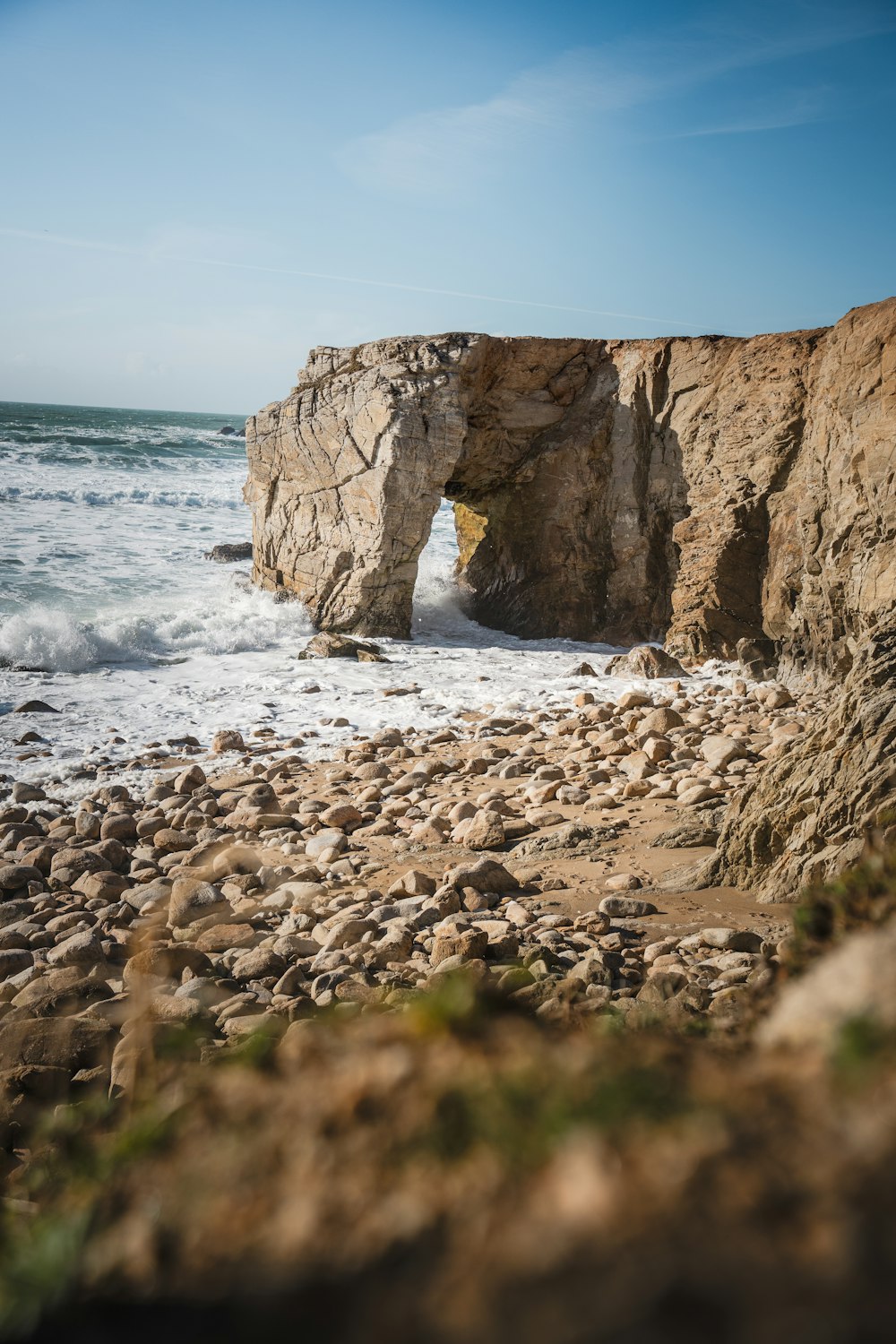 a rocky beach with a small cave in the middle of it