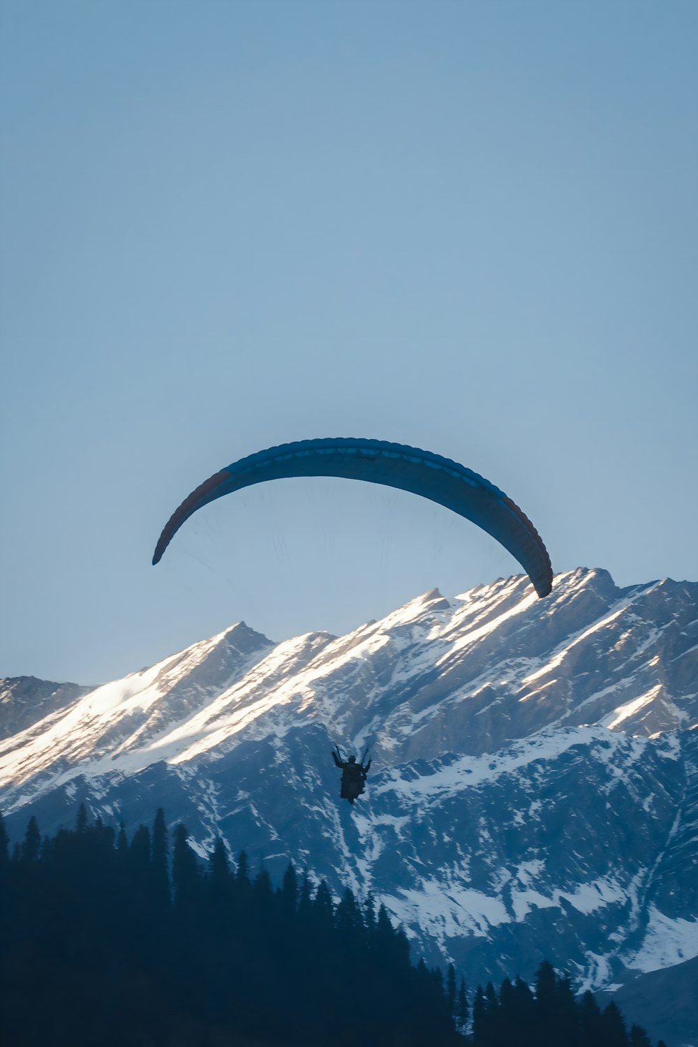 a paraglider is flying over a mountain range