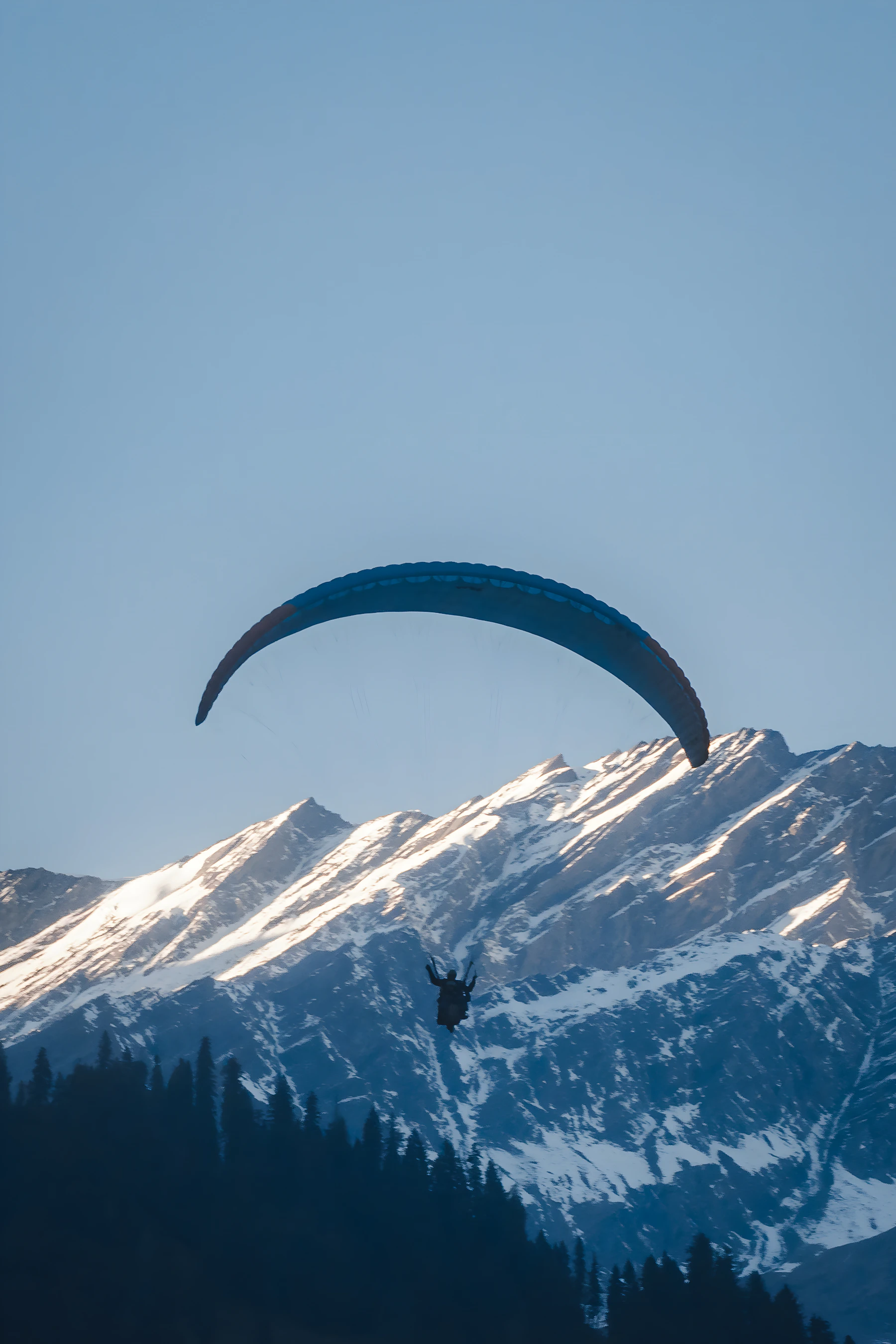 Sample photograph of a paraglider flying against snowy mountains in Manali, Himachal Pradesh