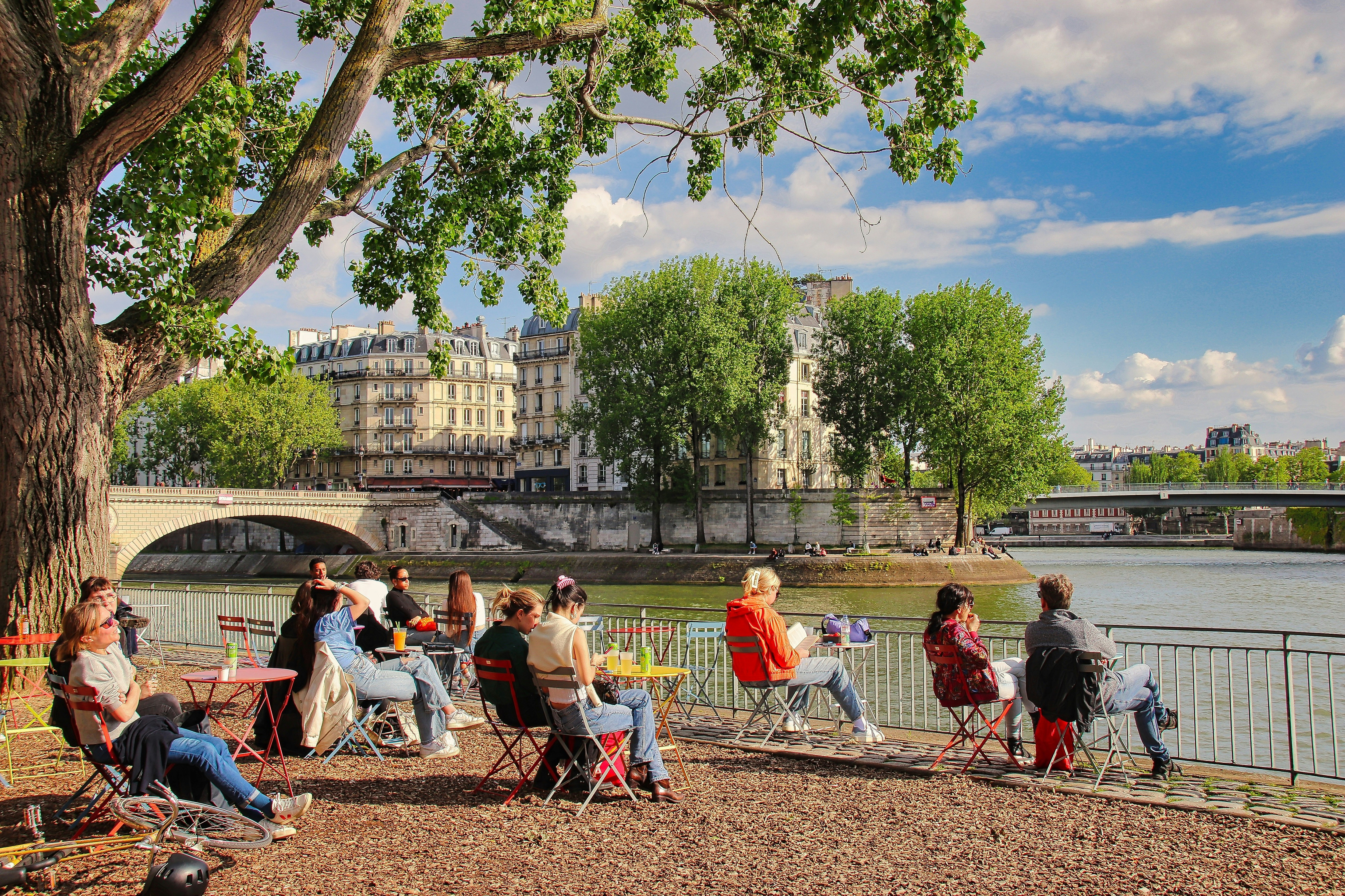a group of people sitting on a bench next to a river