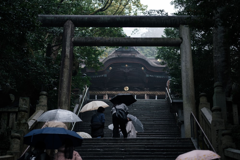 a group of people with umbrellas walking up a set of stairs