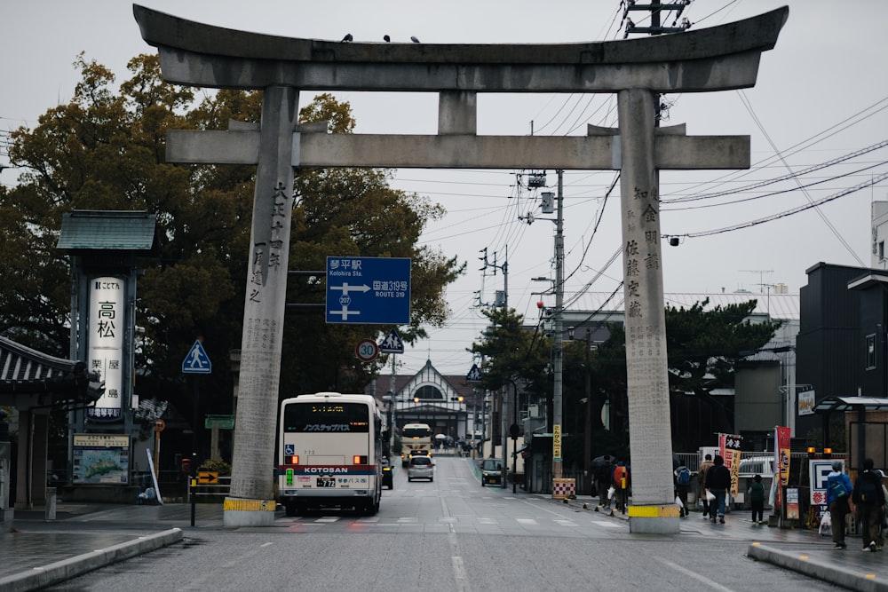 a bus driving down a street under a tall arch