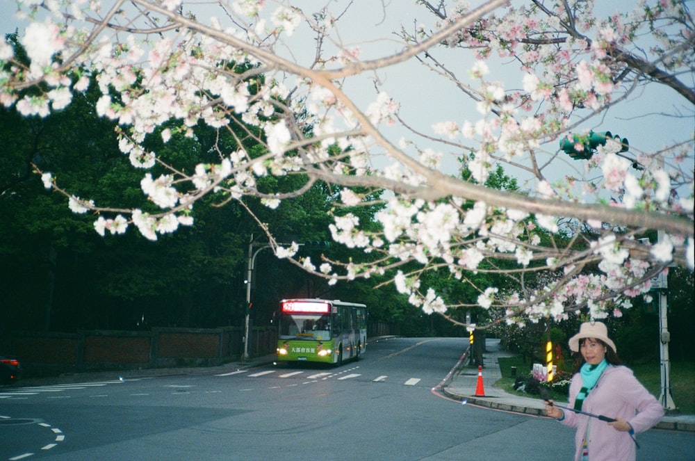 a woman standing on the side of a road next to a bus