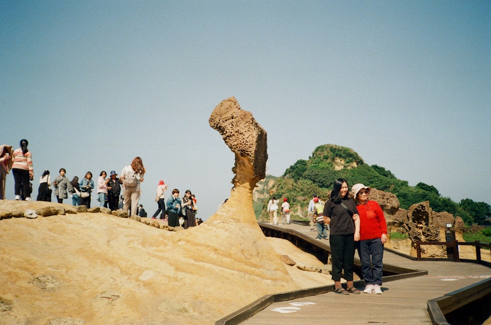 a group of people standing next to a large rock formation