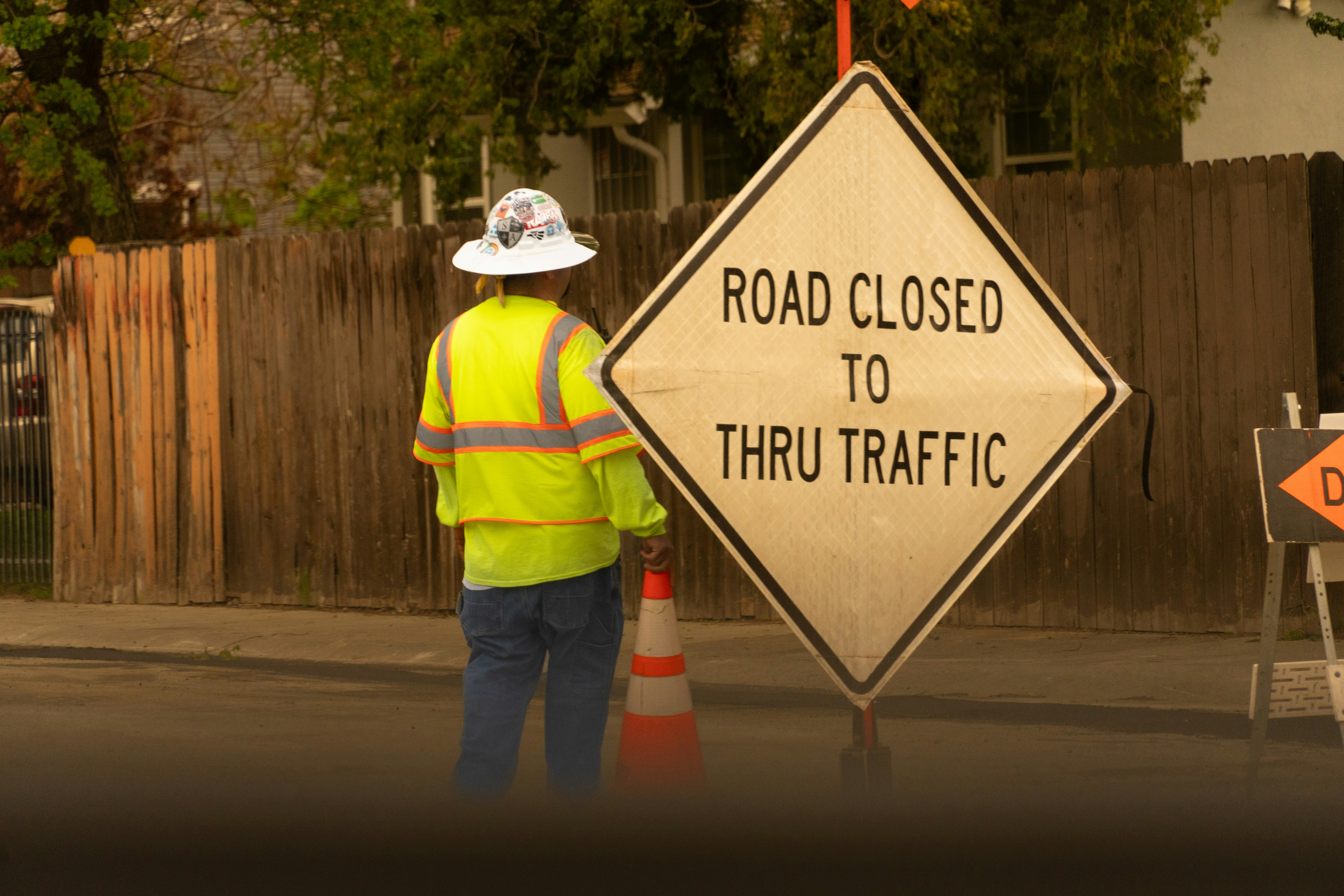 a construction worker standing next to a road closed to thru traffic sign