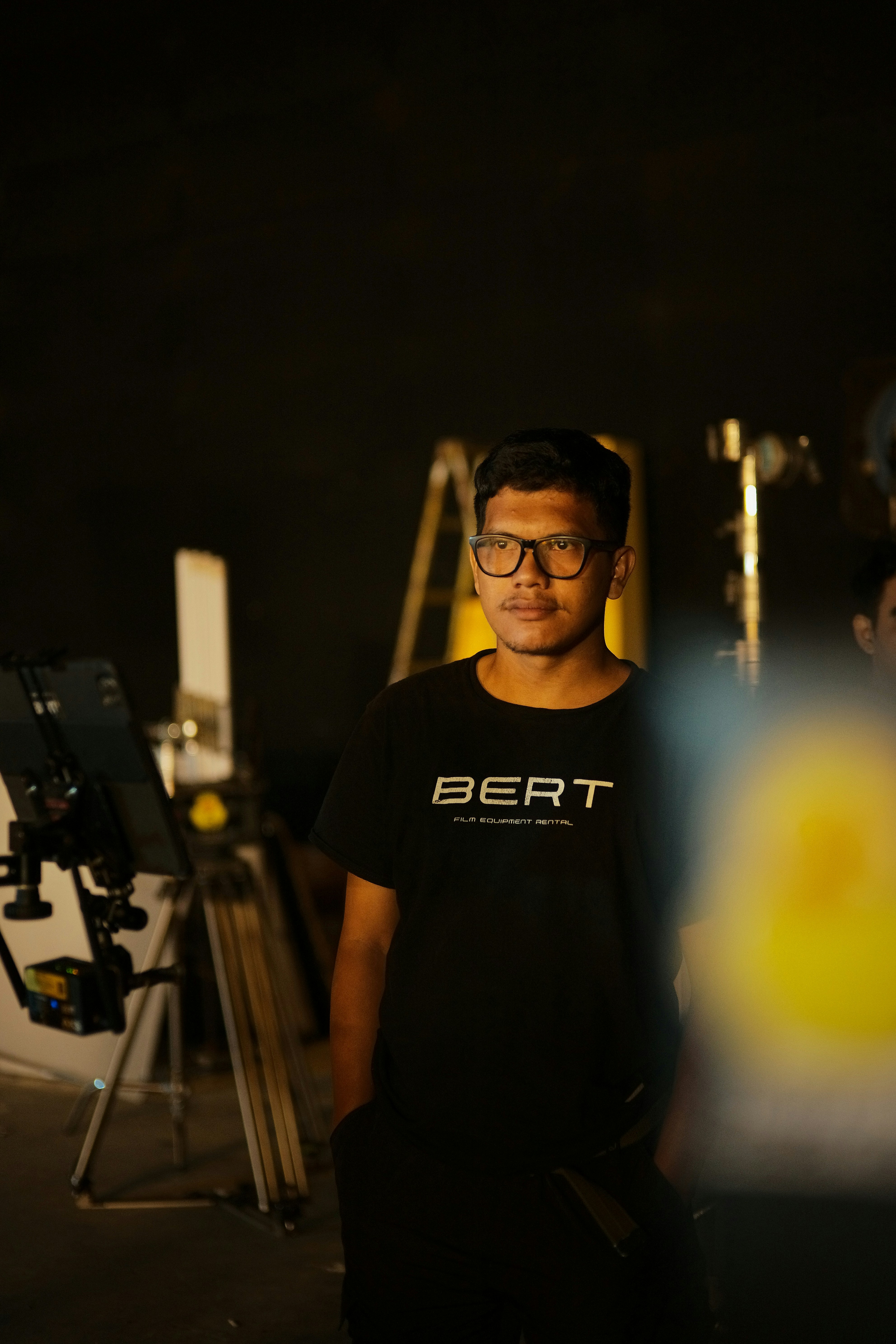 Man wearing dark oversized t-shirt, moody studio background, low-key lighting, dark walls